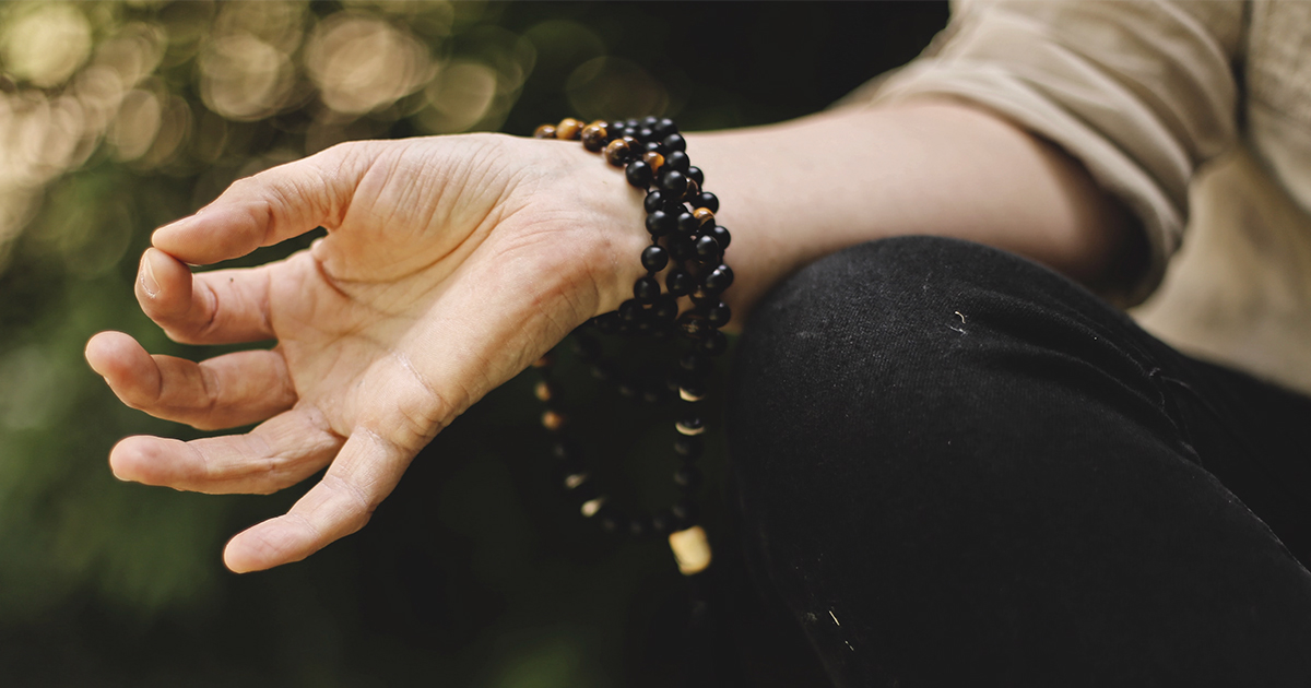 A hand resting on the knee. The fingers are forming the Gyan mudra